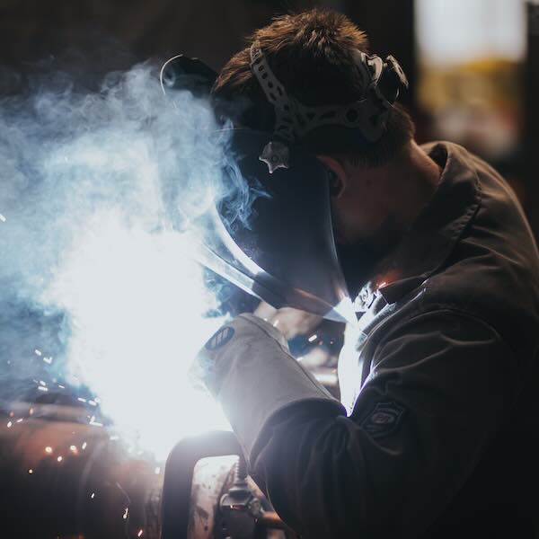 A welder technician welding centered in the image with the light from the arc. A welder technician welding centered in the image with the light from the arc.